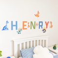 Load image into Gallery viewer, Close view of personalised name fabric wall stickers featuring colourful letters and dinosaurs