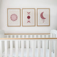 Load image into Gallery viewer, Set of three prints showing rose red sun, moon phases and crescent moon with stars, above cot display