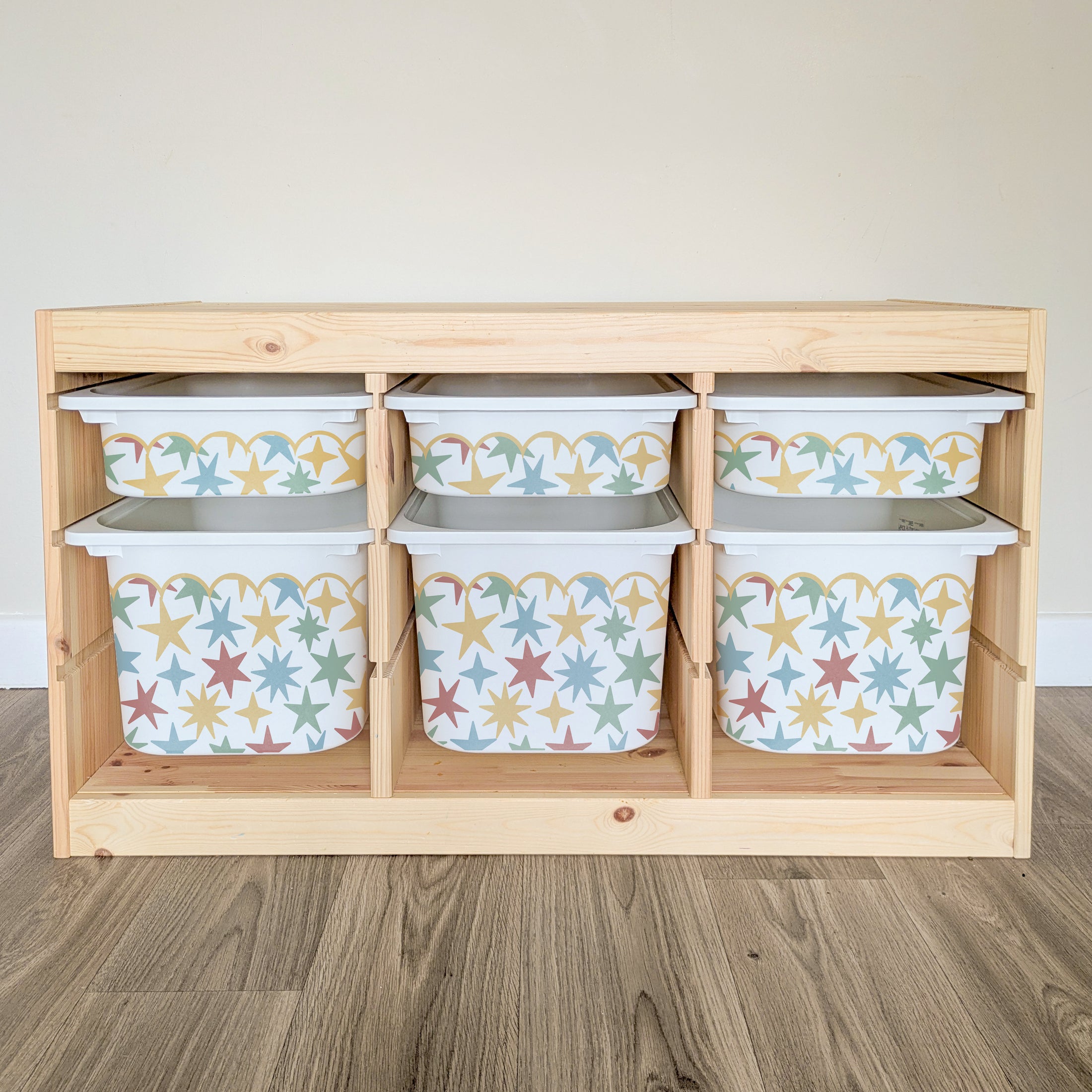 A wooden shelf with six compartments, each containing a white plastic bin with a star pattern design.