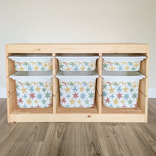 A wooden shelf with six compartments, each containing a white plastic bin with a star pattern design.
