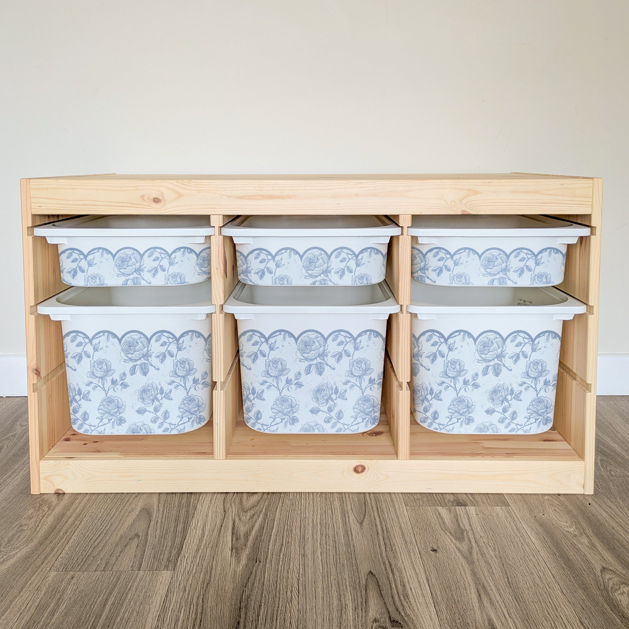 A wooden shelf with six white storage bins arranged in two rows of three, each bin featuring a blue floral pattern.