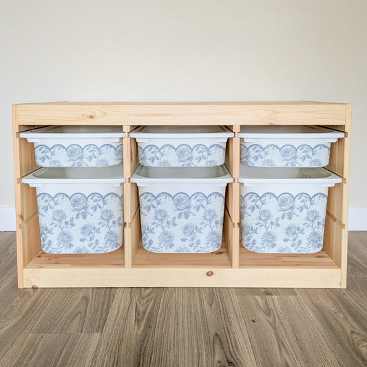 A wooden shelf with six white storage bins arranged in two rows of three, each bin featuring a blue floral pattern.