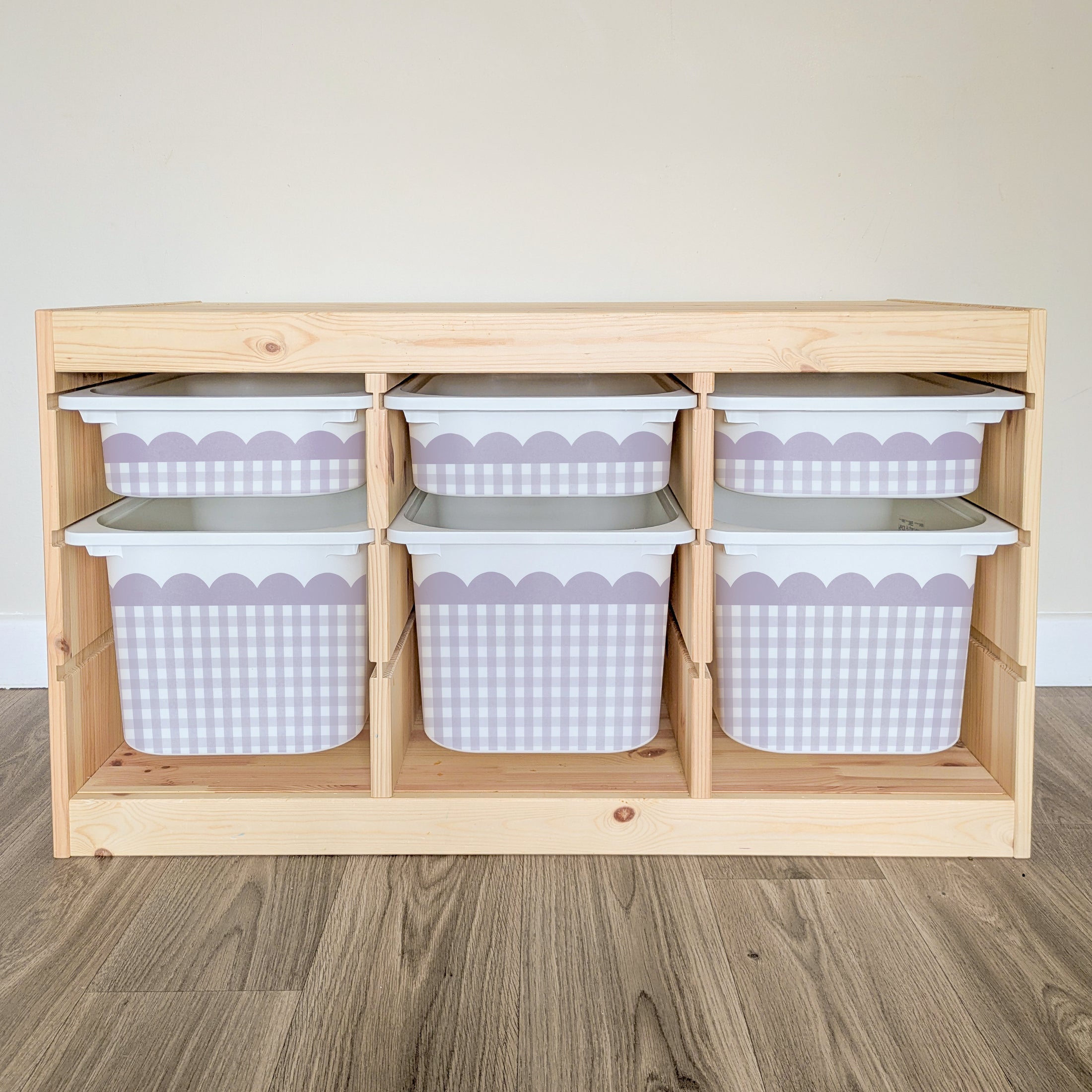 A wooden shelf with six storage bins arranged in two rows of three, each bin has a white and purple checkered pattern.