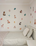 Load image into Gallery viewer, Children's bedroom with wall stickers of animals and nature on a white wall.
