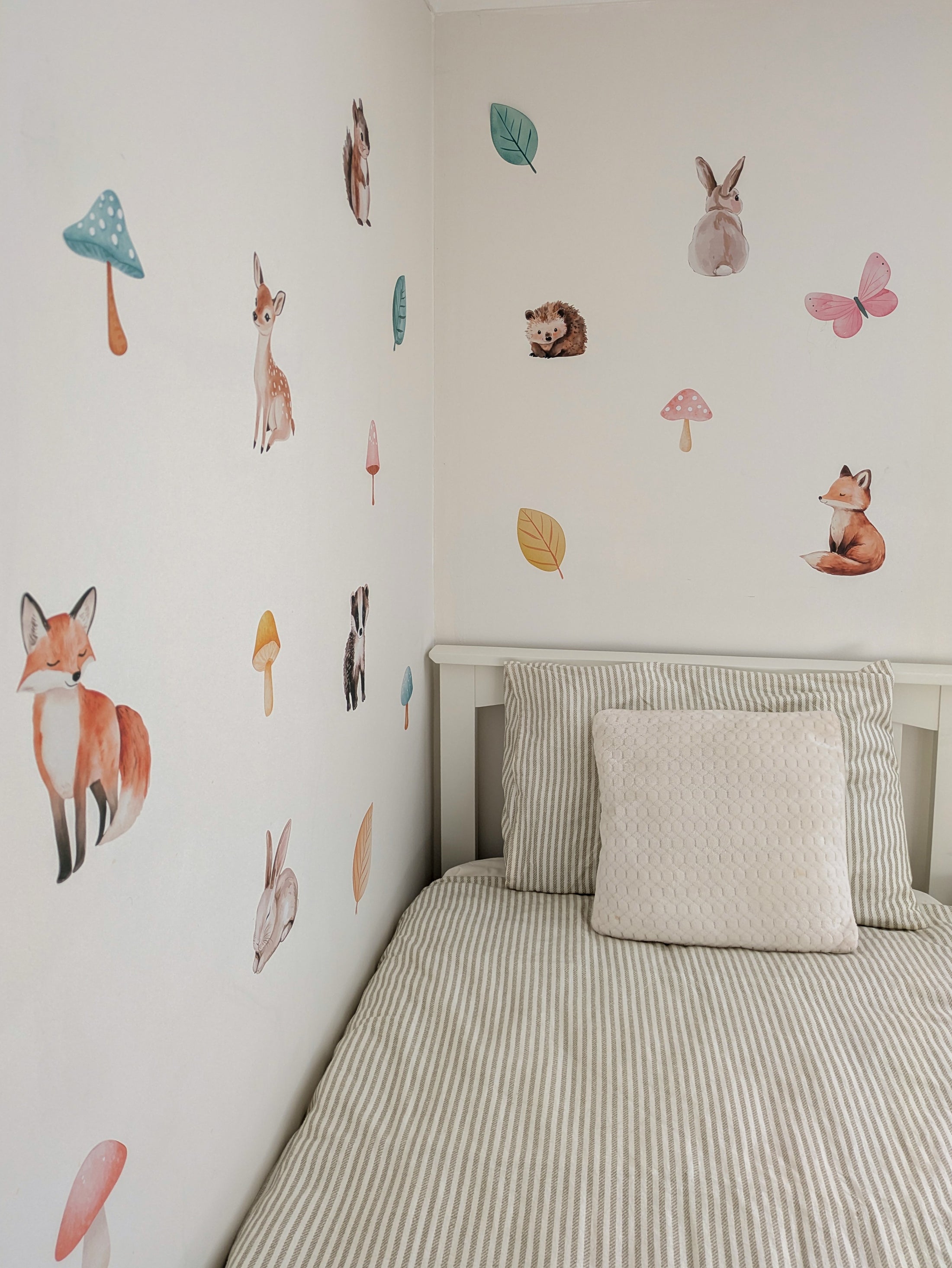 Children's bedroom with woodland animal-themed wall decals on a white wall.