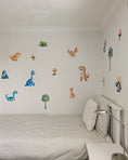 Load image into Gallery viewer, Children's room with dinosaur wall decals on a white wall.

