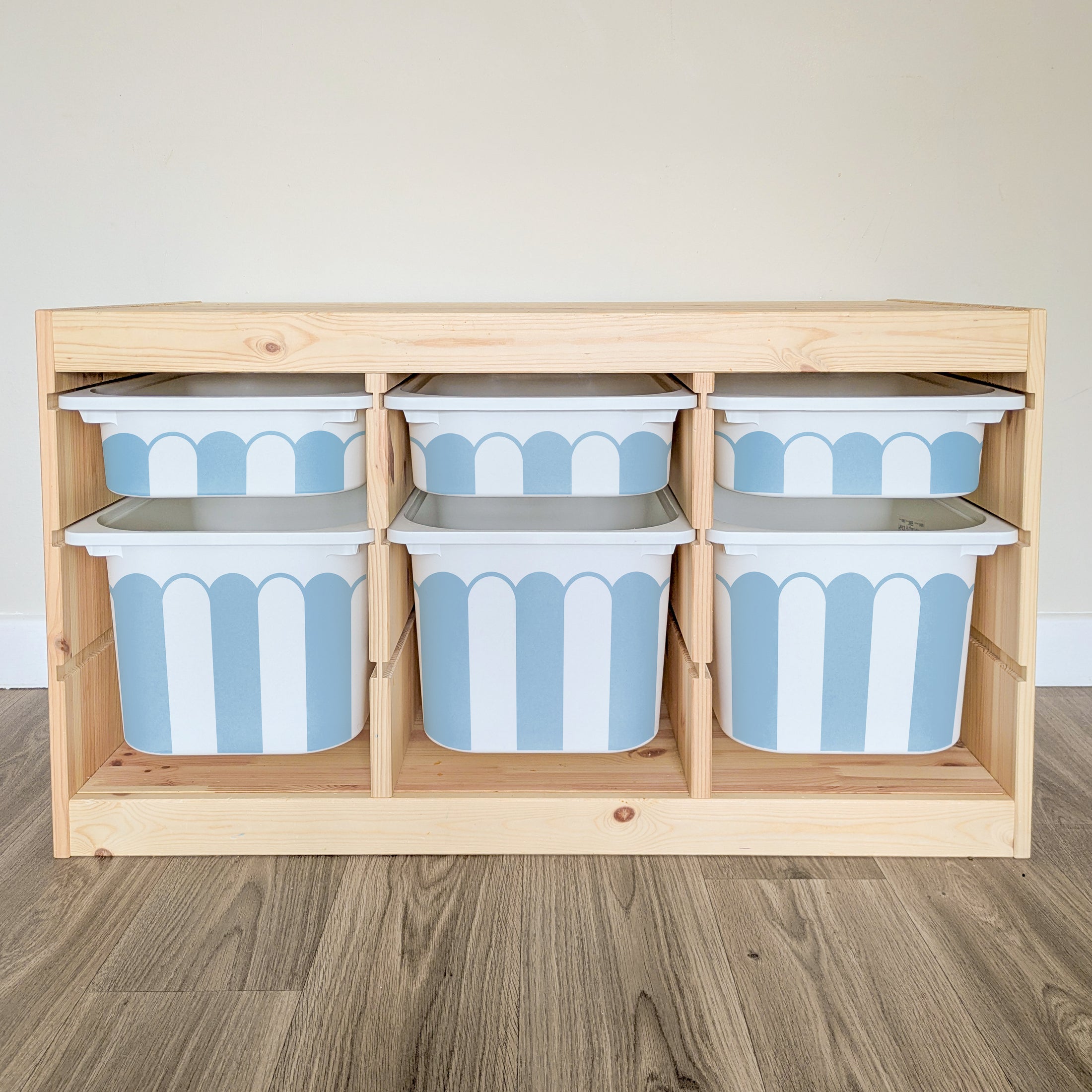 A wooden shelf with six blue and white striped storage bins arranged in two rows of three.