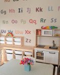 Load image into Gallery viewer, Removable A–Z fabric letter decals arranged above Montessori shelves.
