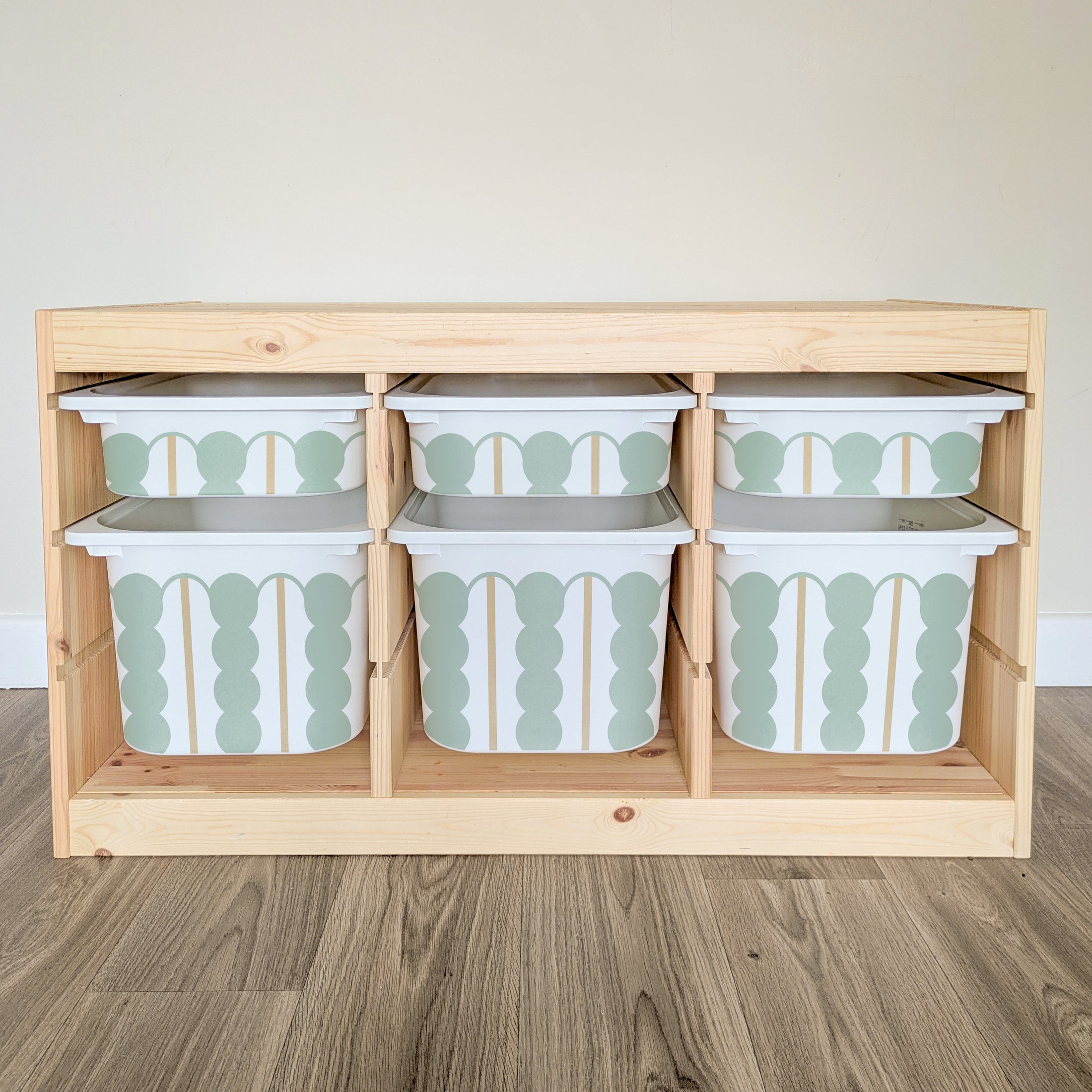 A wooden shelf with six drawers, each containing a white and green patterned storage container.