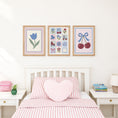 Load image into Gallery viewer, Cherry and floral nursery prints above a bed with pink striped bedding
