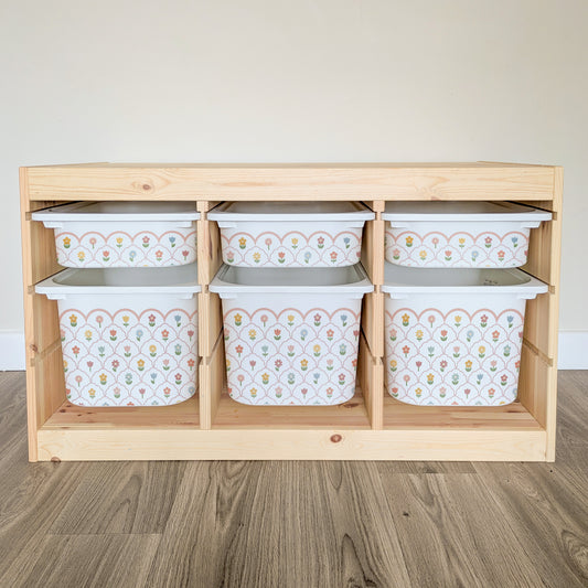 A wooden shelf with six white storage bins arranged in two rows of three, each bin featuring a floral pattern.