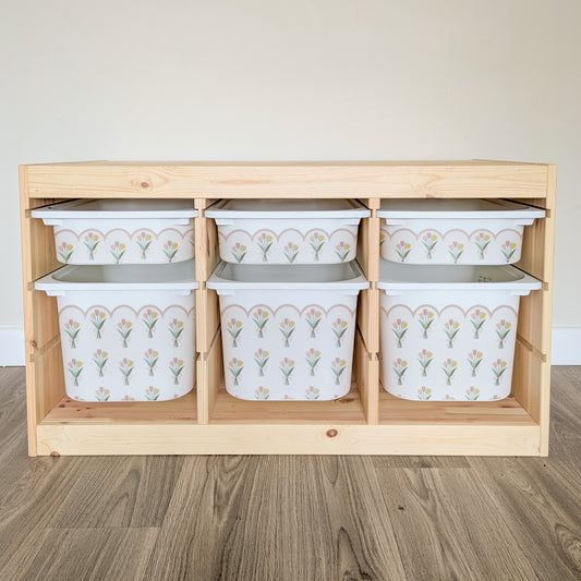 A wooden shelf with six white plastic bins arranged in two rows, each bin featuring a floral pattern.