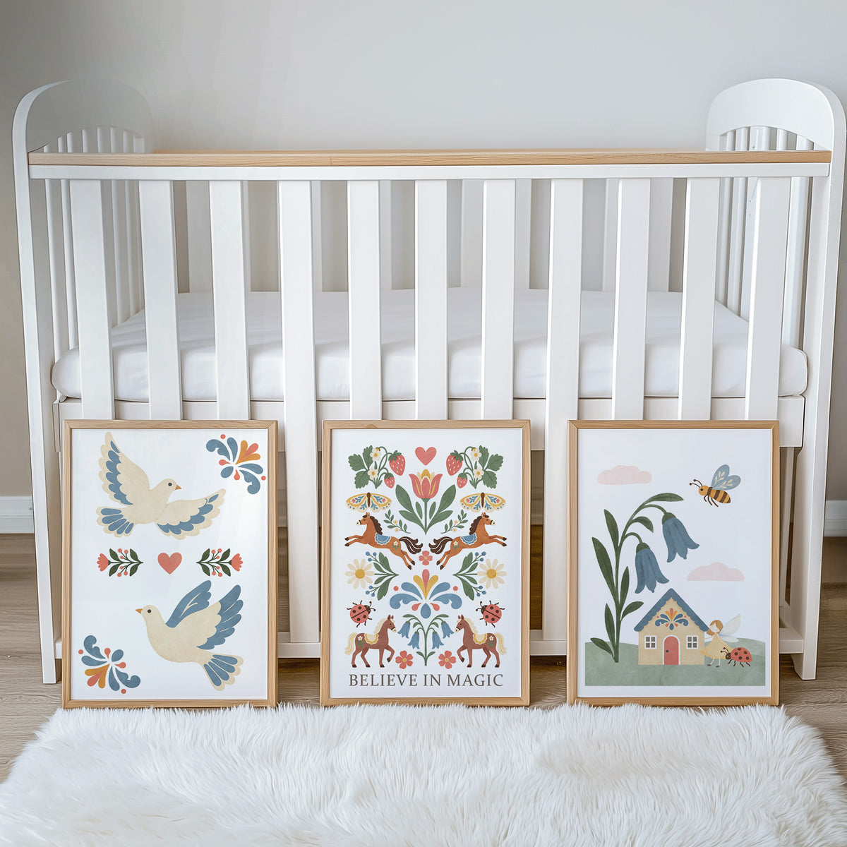 Three folk art prints styled beside a cot