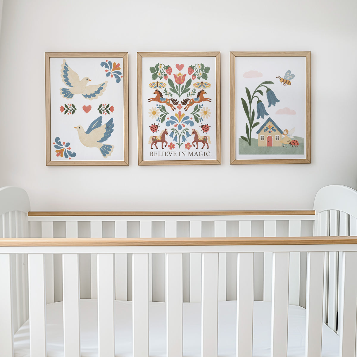 Folk art nursery prints displayed on a wall above a cot