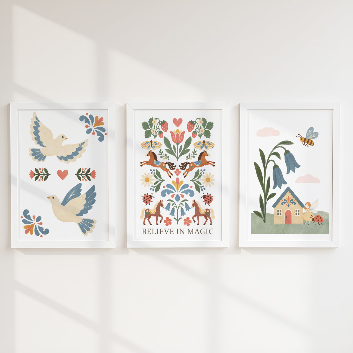 Close-up of three folk art prints showing doves, floral horses with Believe in Magic wording and a bluebell fairy cottage