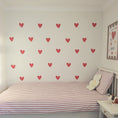 Load image into Gallery viewer, Children's bedroom with red heart decals on a white wall, striped bedding, and a teddy bear.
