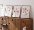 Load image into Gallery viewer, a wooden cabinet with three framed pictures on top of it
