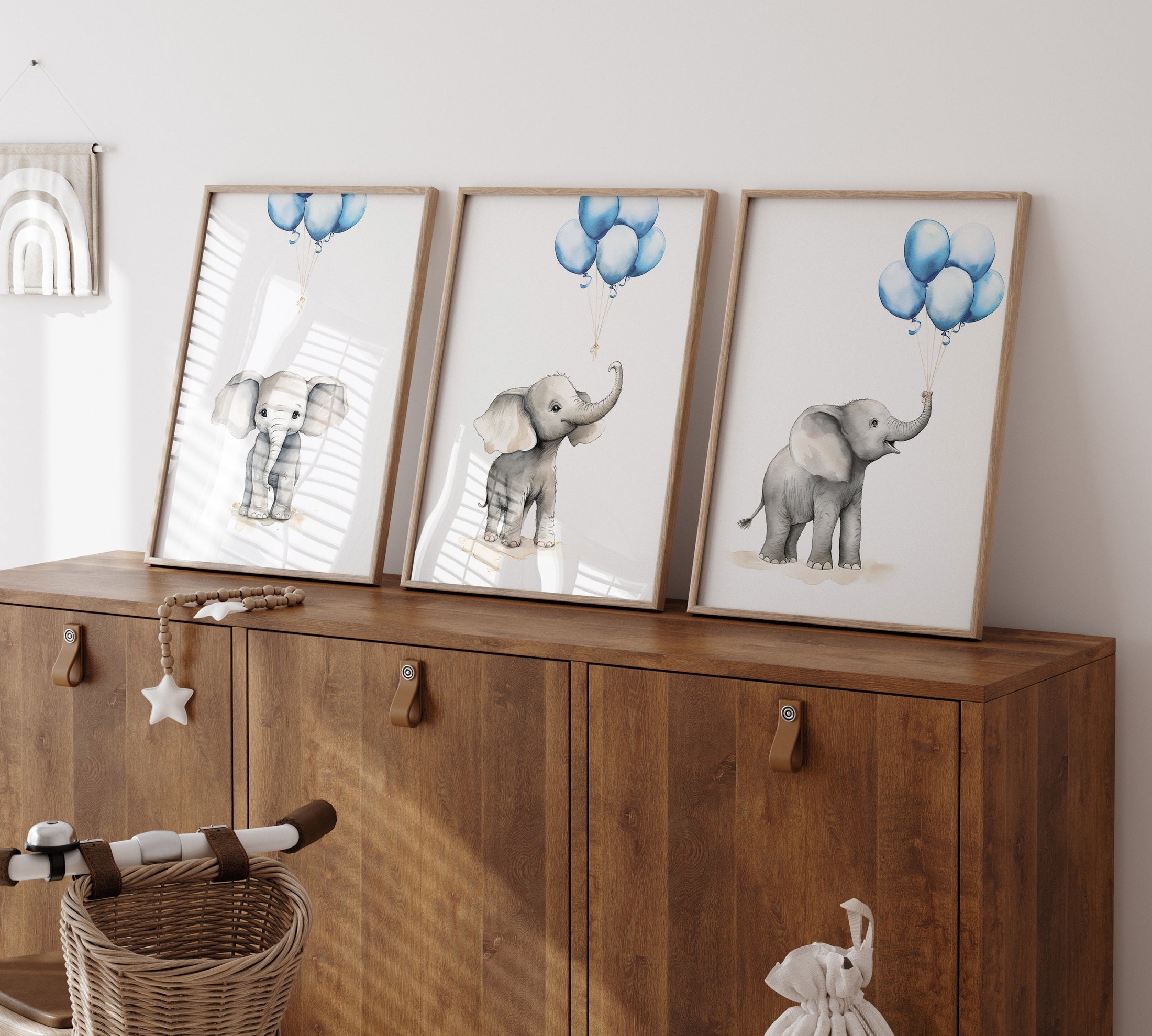 three framed pictures of elephants on a wooden cabinet