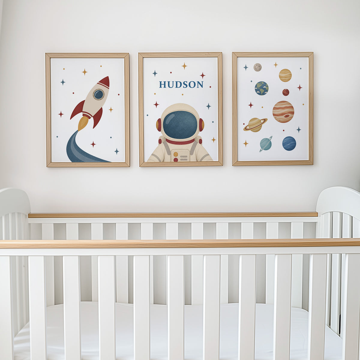 Set of three prints showing rocket, personalised astronaut and planets, above cot display