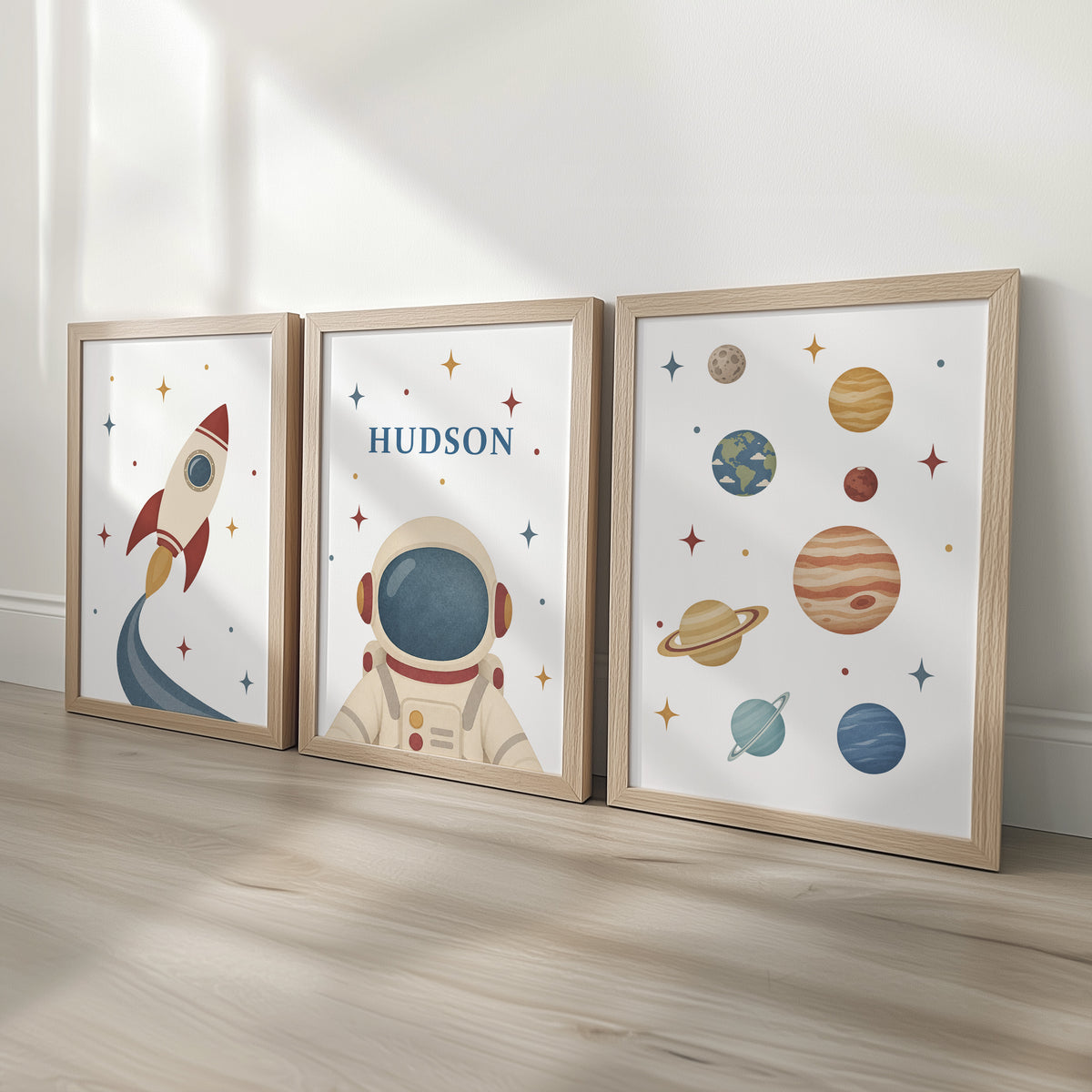 Set of three retro space prints showing rocket, personalised astronaut and planets, oak frames display