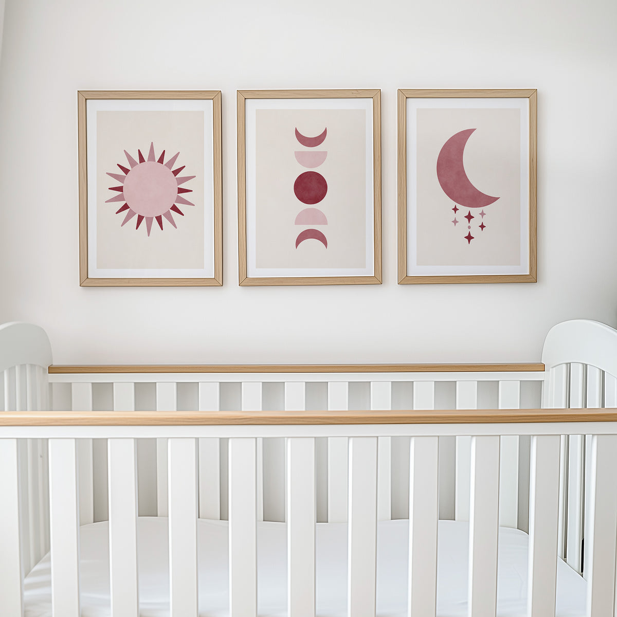 Set of three prints showing rose red sun, moon phases and crescent moon with stars, above cot display