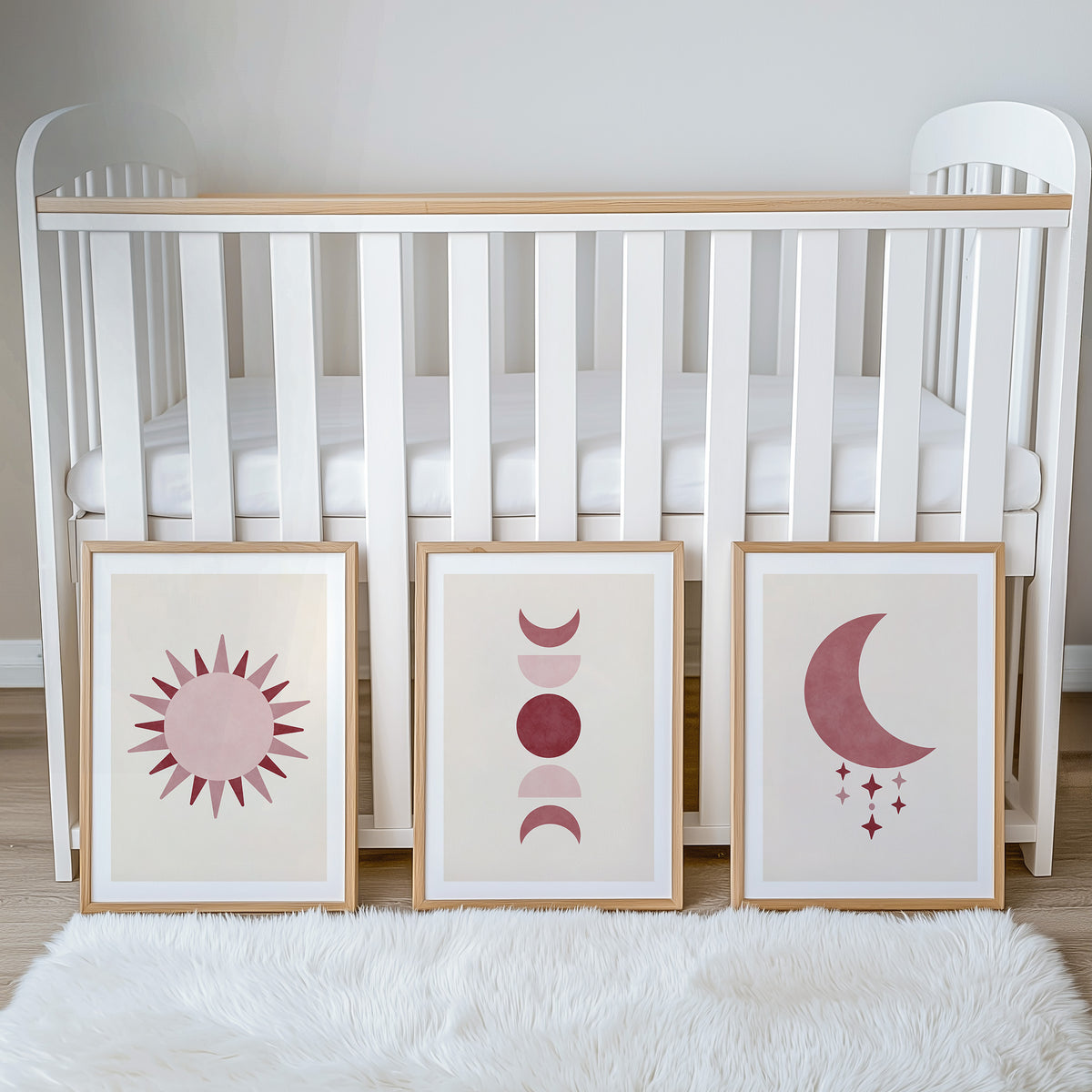 Set of three prints showing rose red sun, moon phases and crescent moon with stars, beside cot display