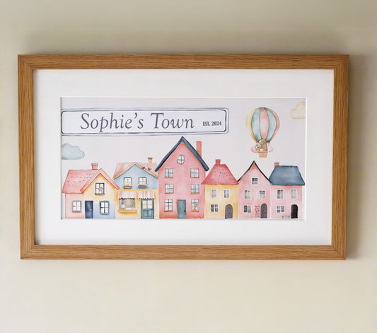 Personalised framed print featuring a charming watercolor design of colourful houses and a hot air balloon in a oak frame with mount.