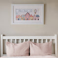 Load image into Gallery viewer, Personalised Tiny Town framed print hanging above a child’s bed in a pastel-colored bedroom.
