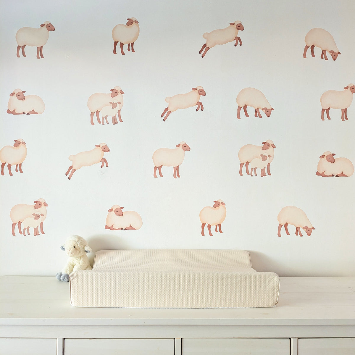 Set of 18 sheep fabric wall stickers arranged above a nursery changing table