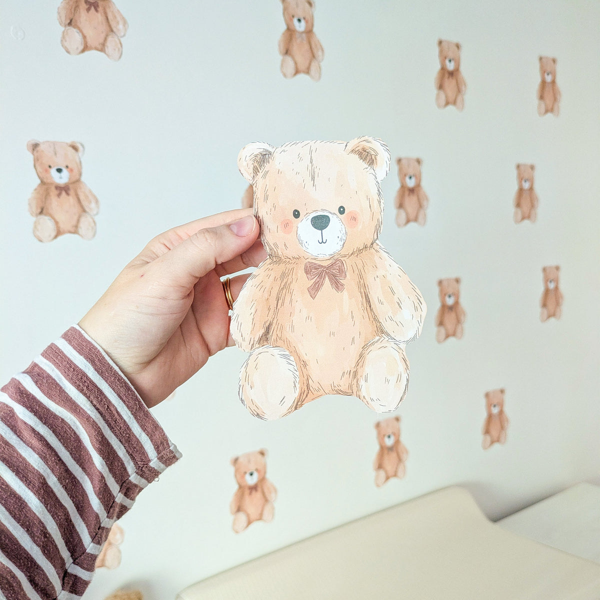 Close-up of a mini teddy bear fabric wall sticker held against the nursery wall
